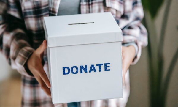 Woman holding box with inscription Donate in light room