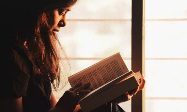 Woman Reading a Book Beside the Window